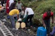 脱線した列車から漏れたディーゼル燃料を容器持参で持ち帰る人々（インド）